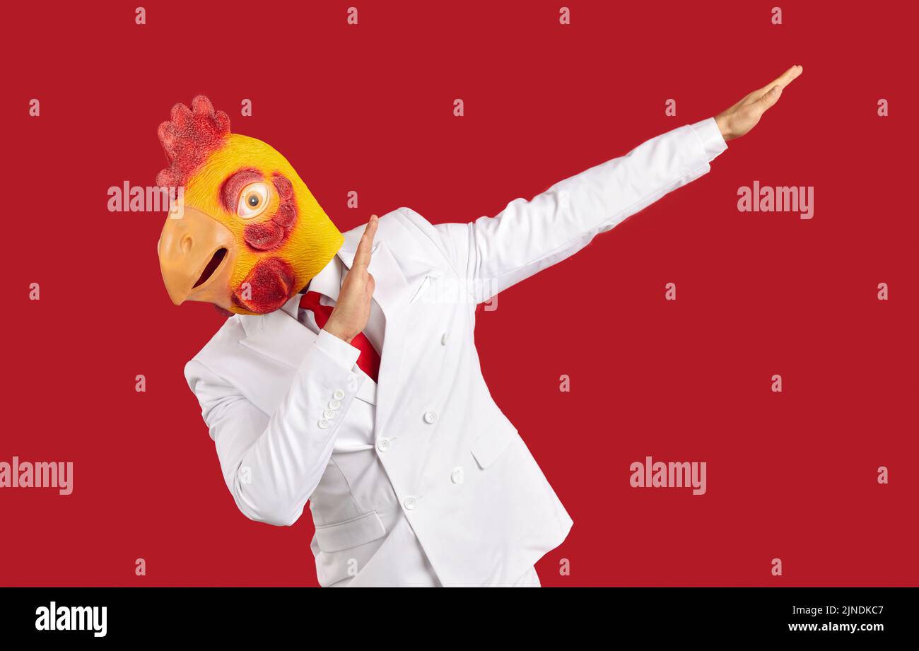 Weirdo man in chicken mask makes movement of famous internet meme about victory on red background. Stock Photo