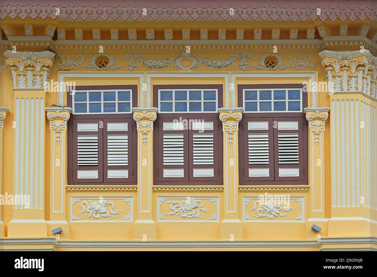 Conserved Peranakan shophouse louvered windows with distinctive Straits Chinese & rococo architecture, with lucky Chinese symbols on plasterboard Stock Photo