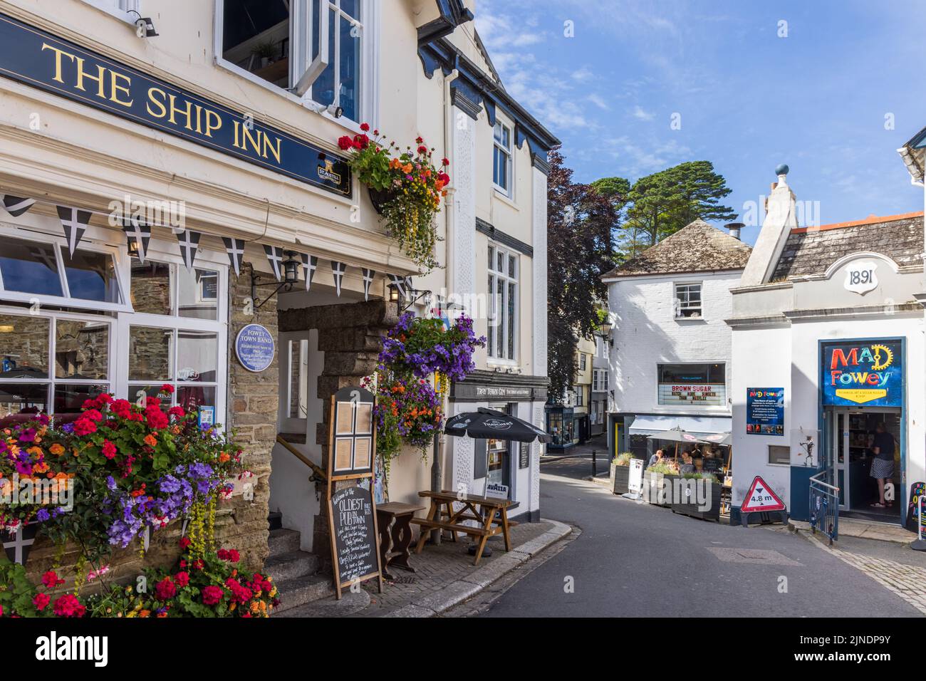A street scene with colourful floral displays outside the 16th century Ship Inn, a historic pub in Fowey, Cornwall. Stock Photo