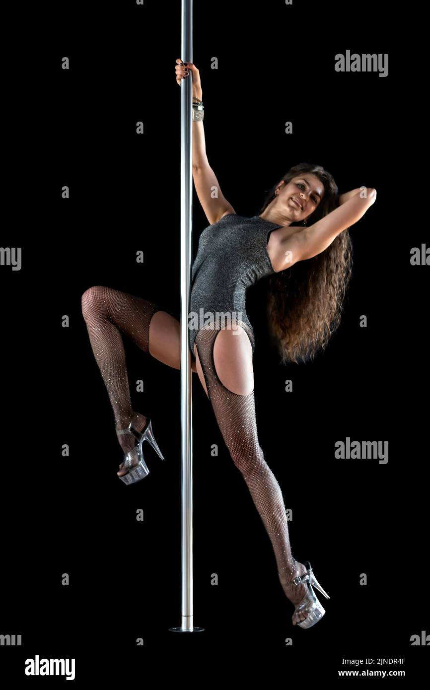 High heels dancer. Young sexy slim brunette woman pole dancing on black background Stock Photo