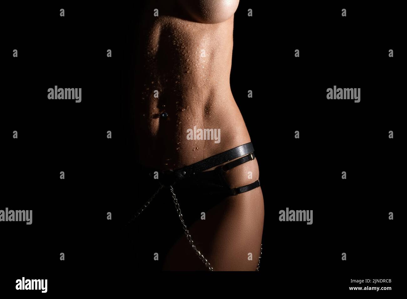 Beautiful athletic young woman body on black. Perfect body with water drops. Stock Photo