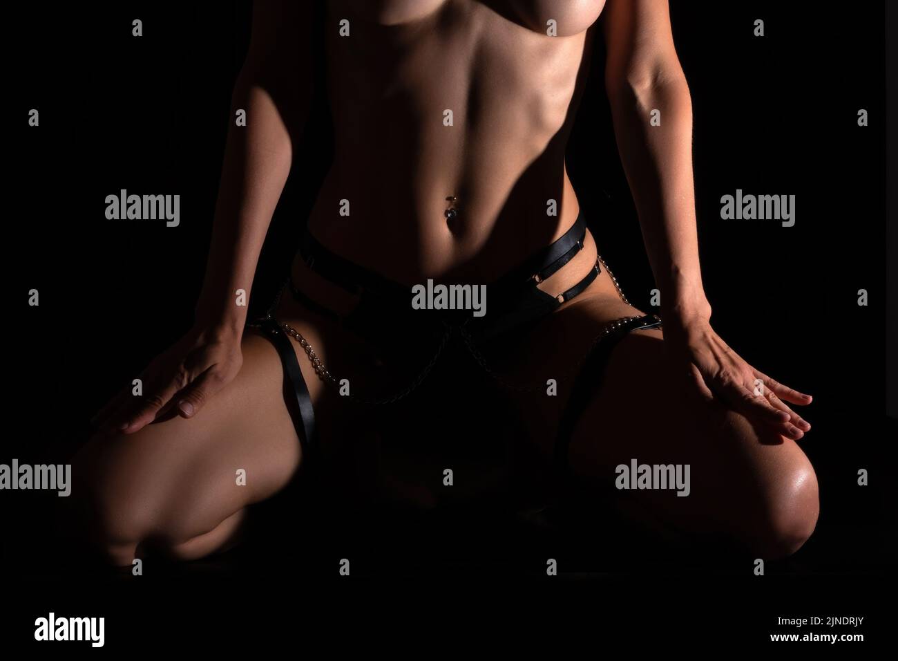 Beautiful athletic young woman body on black. Nude body with water drops. Stock Photo