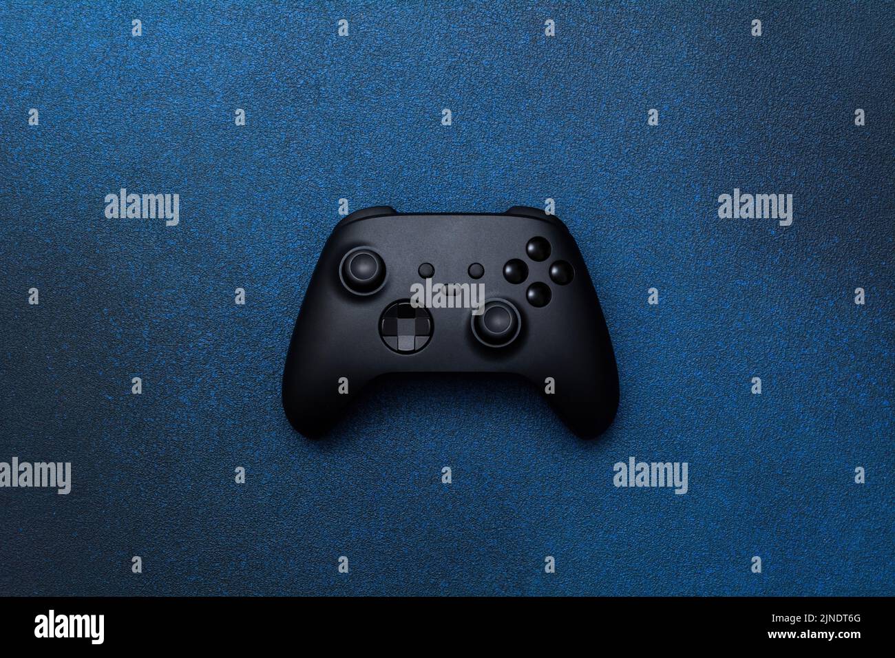 Game controller on a blue background. Black joystick for computer games top view. Stock Photo