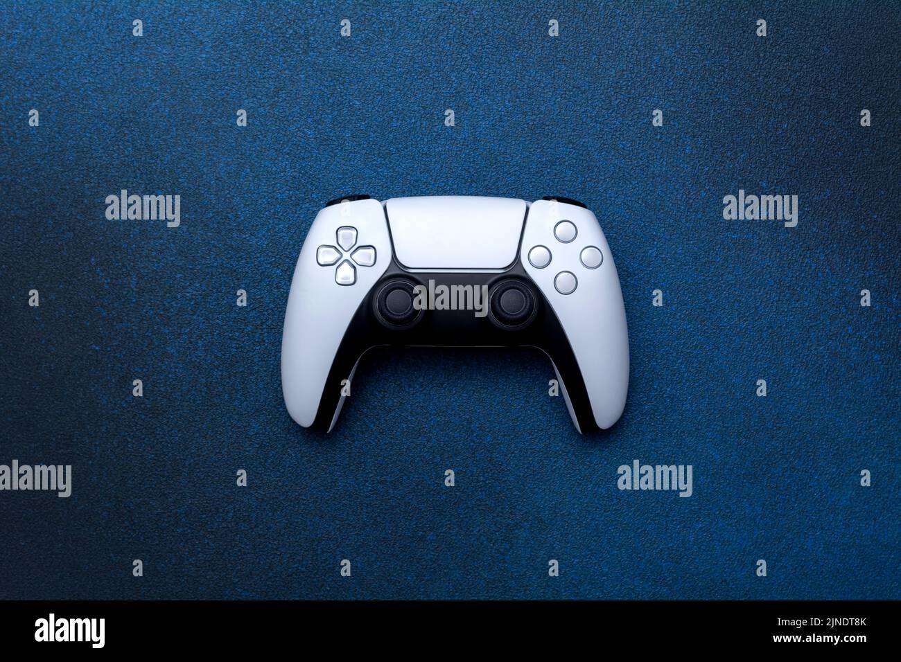 Game controller on a blue background. White joystick for computer games top view. Stock Photo