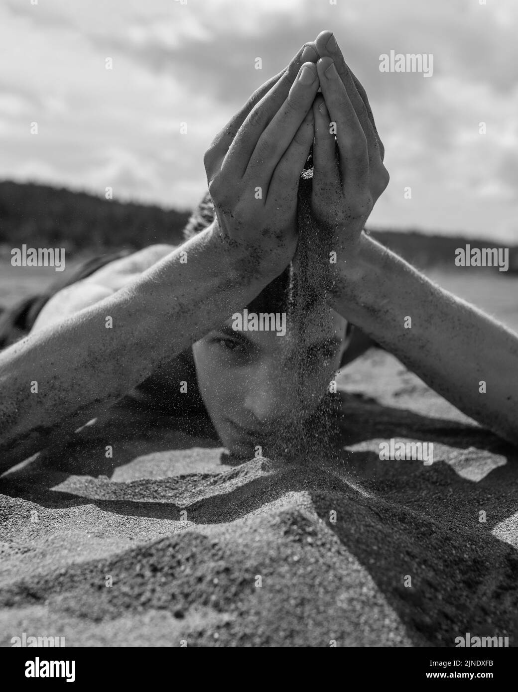 Man lying on his stomach and pouring sand through hands in the desert Stock Photo