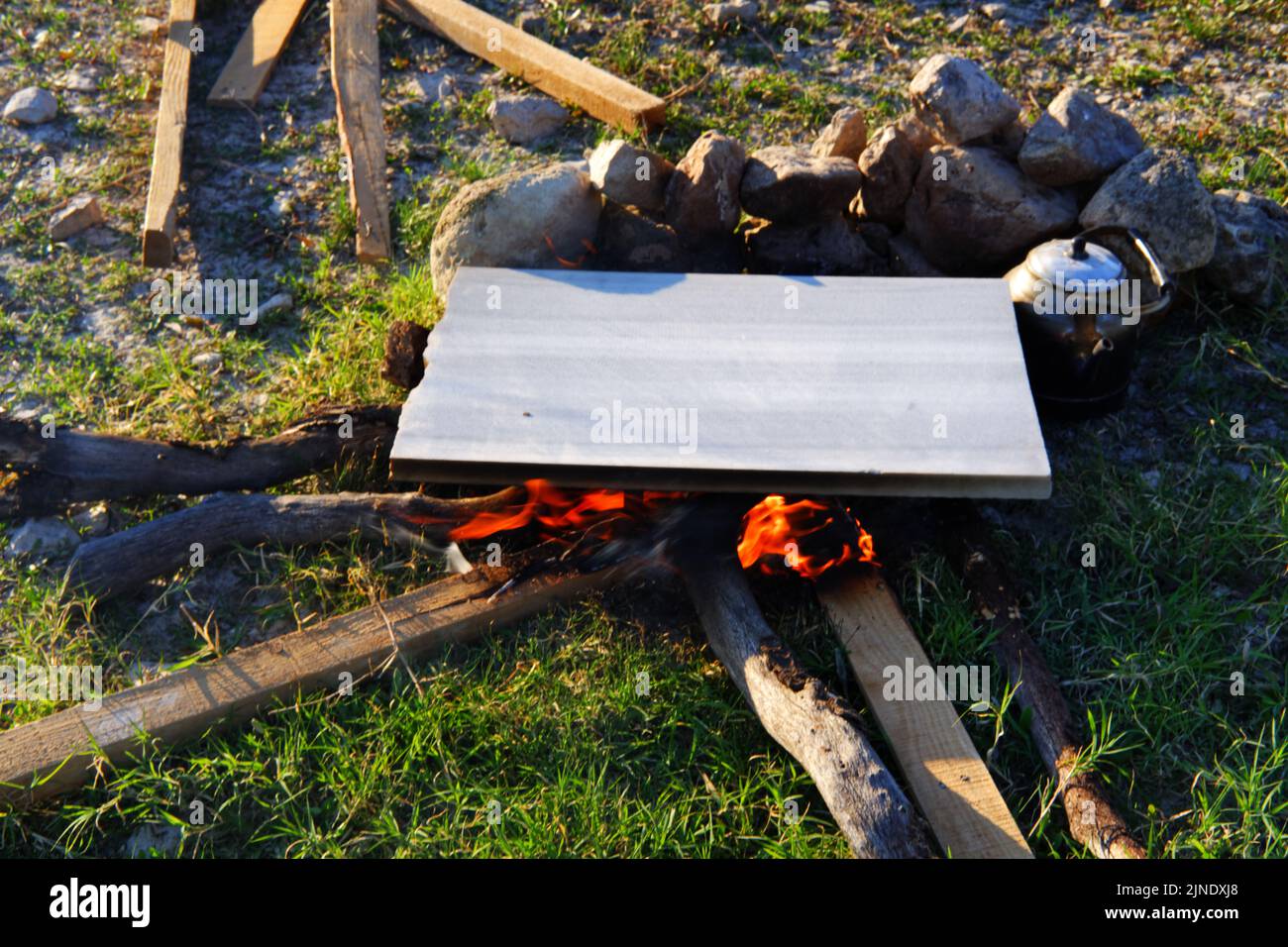Marble on camp fire for cooking and teapot by the fire outdoor Stock Photo