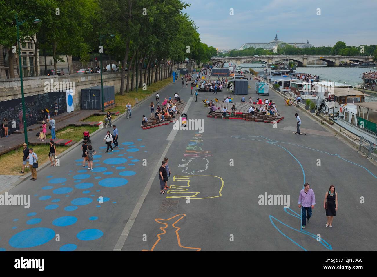 Wide, overhead shot of people hanging out and enjoying the art installations along the Seine riverside. Beautiful summer day outdoor in Paris, France. Stock Photo
