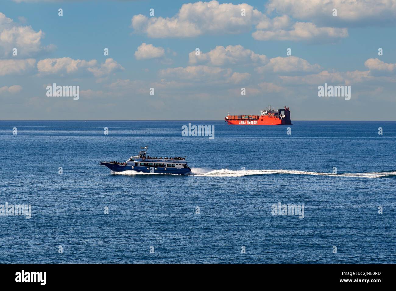 A tourist boat and a container ship of the Linea Messina, a shipping company based in Genoa, on the sea horizon, Nervi, Genoa, Liguria Stock Photo