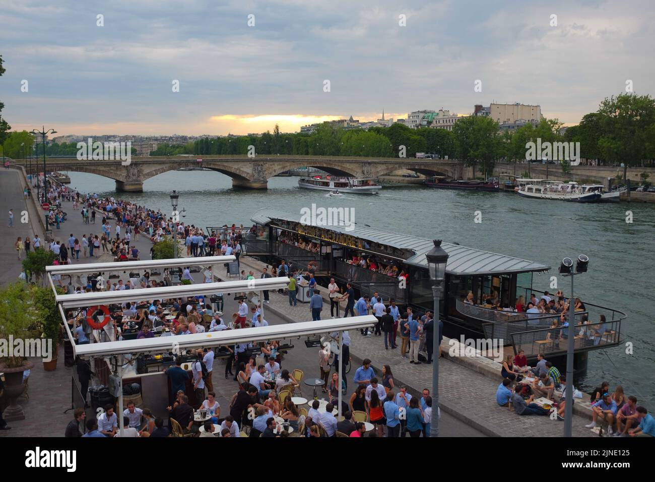 Huge crowd of people hang out with food and drinks by the Seine river, near Pont de la Concorde. Beautiful summer day outdoor in Paris, France. Stock Photo