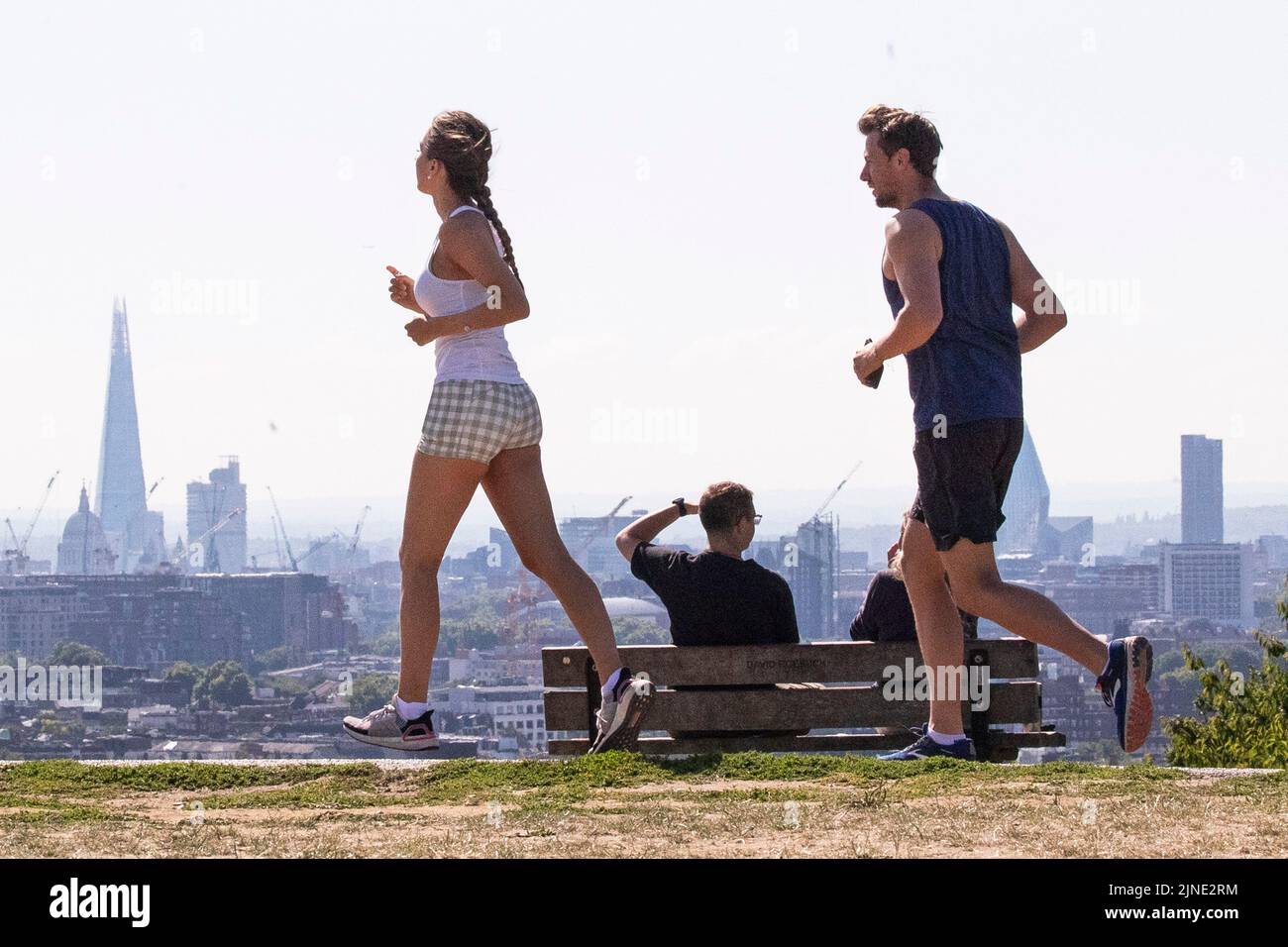 London ,United Kingdom  -09/08/2022. A couple of people run in the sun on a dried out Hampstead Heath, North London as the UK heads into another perio Stock Photo