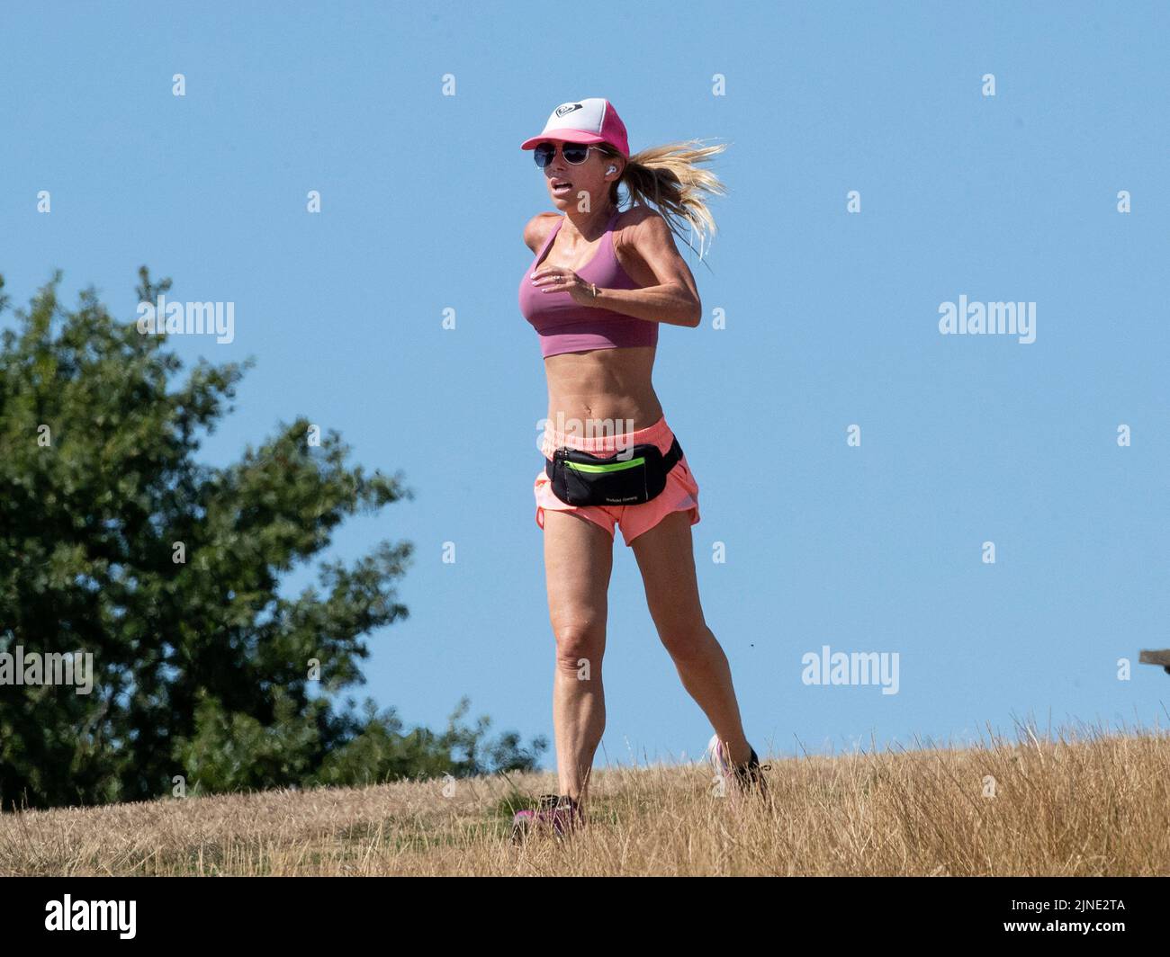 London ,United Kingdom  -09/08/2022. A woman runs in the sun on a dried out Hampstead Heath, North London as the UK heads into another period of hot a Stock Photo