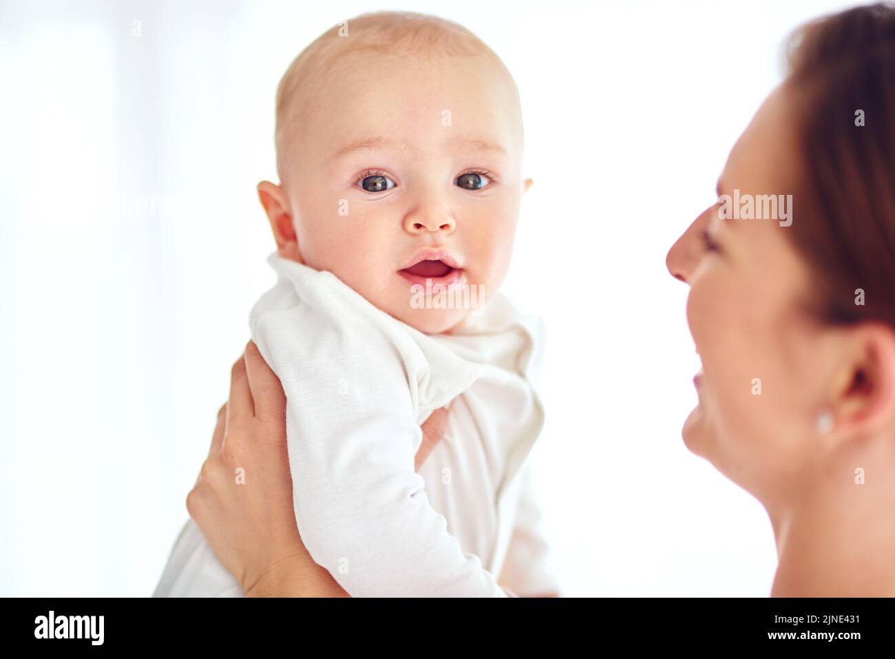 Cute and innocent newborn baby boy bonding with his mom together as a family in studio isolated on a white background. Newborn male child in the hands Stock Photo