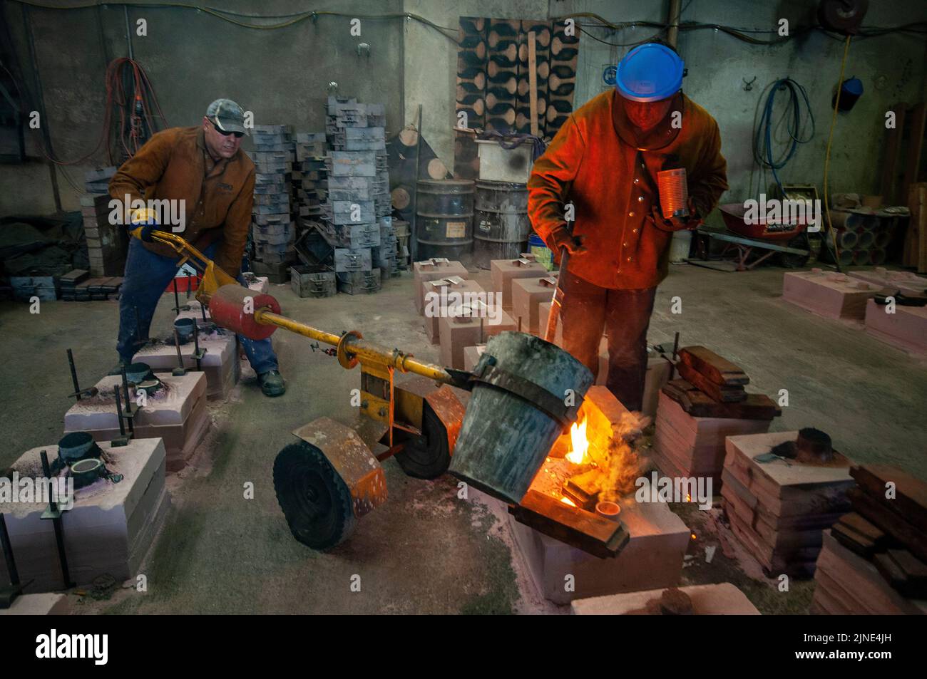 Foundry workers casting molten metal into moulds in a small family foundry in Perth, Western Australia Stock Photo
