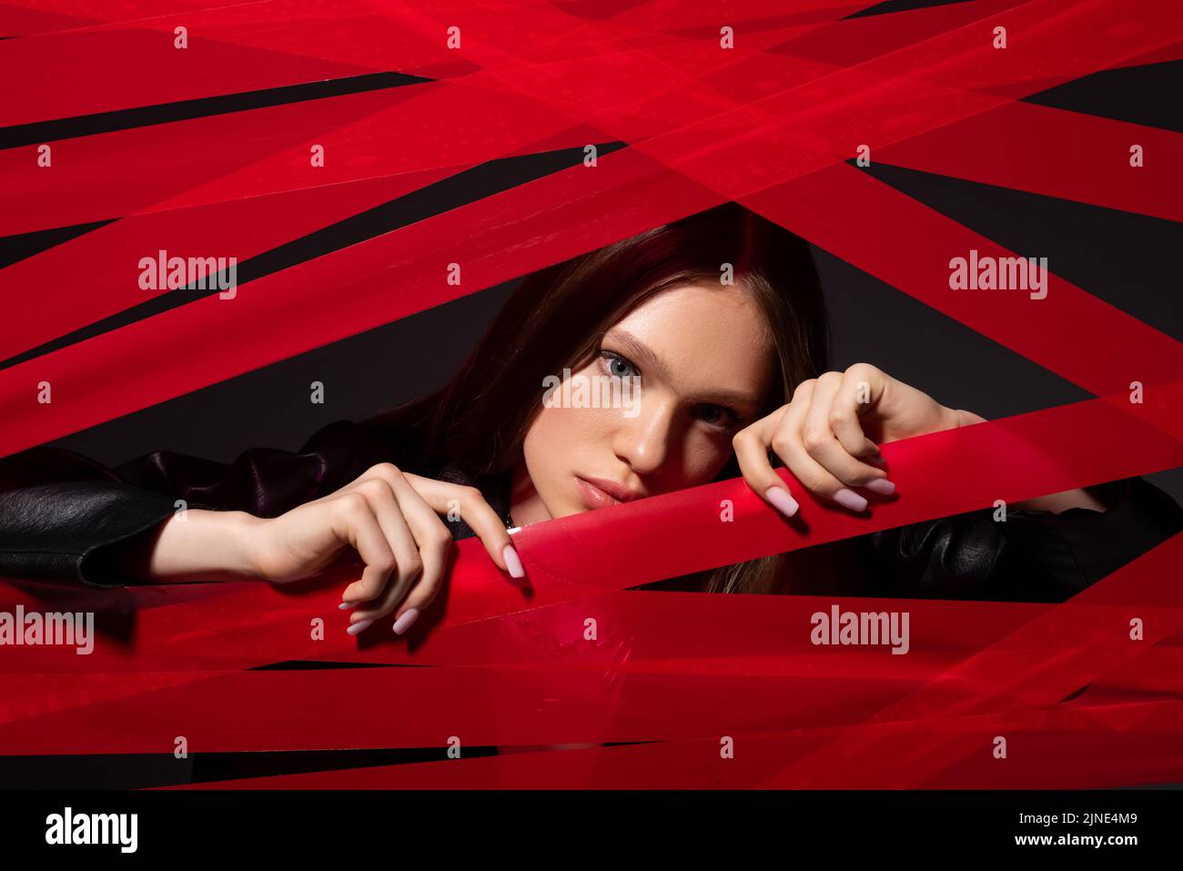 pretty model touching red strips from duct tape isolated on black, recycle fashion concept Stock Photo