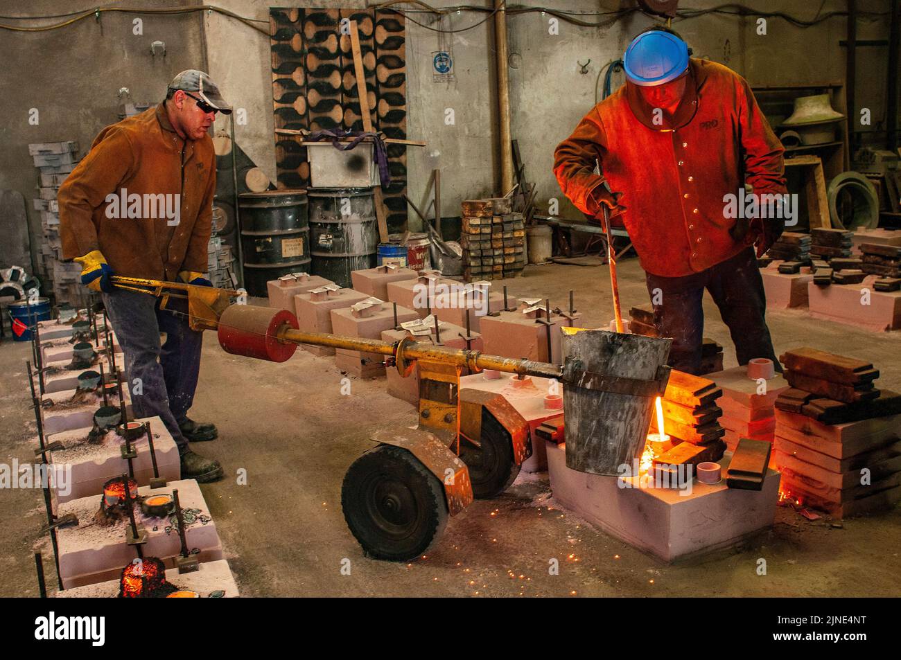 Foundry workers pouring molten metal into moulds  in a small family foundry in Perth, Western Australia Stock Photo