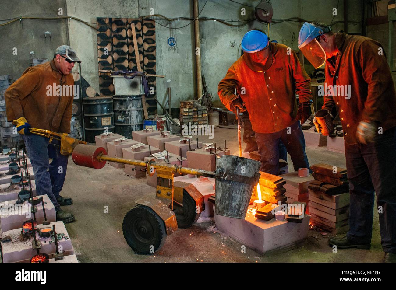 Foundry workers casting molten metal into moulds in small family foundry in Perth, Western Australia Stock Photo