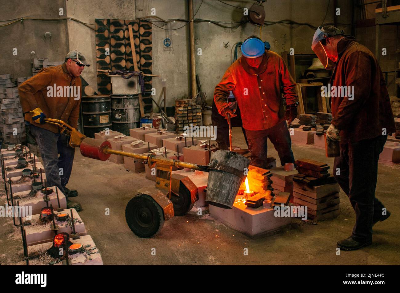 Foundry workers casting molten metal into moulds in small family foundry in Perth, Western Australia Stock Photo