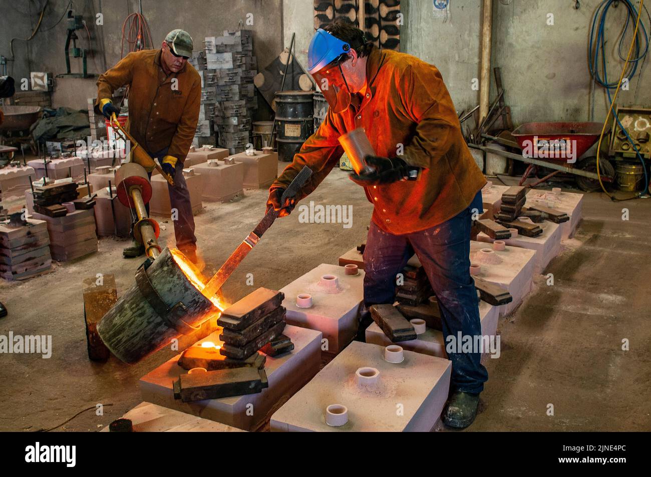Foundry workers pouring molten metal into moulds  in a small family foundry in Perth, Western Australia Stock Photo