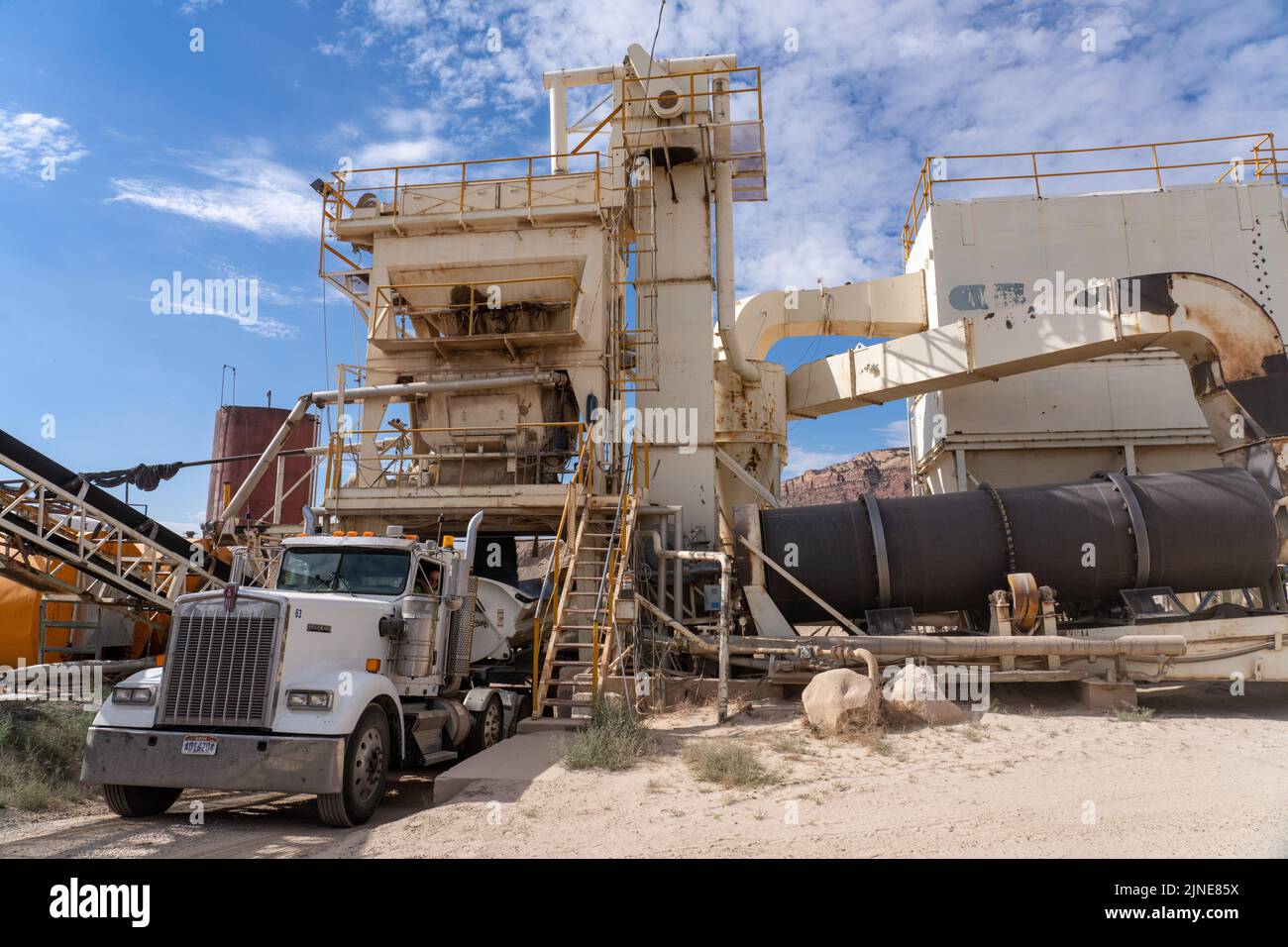 A semi truck gets a load of asphalt from the mixer unit of an asphalt batchmix plant near Moab, Utan. Stock Photo