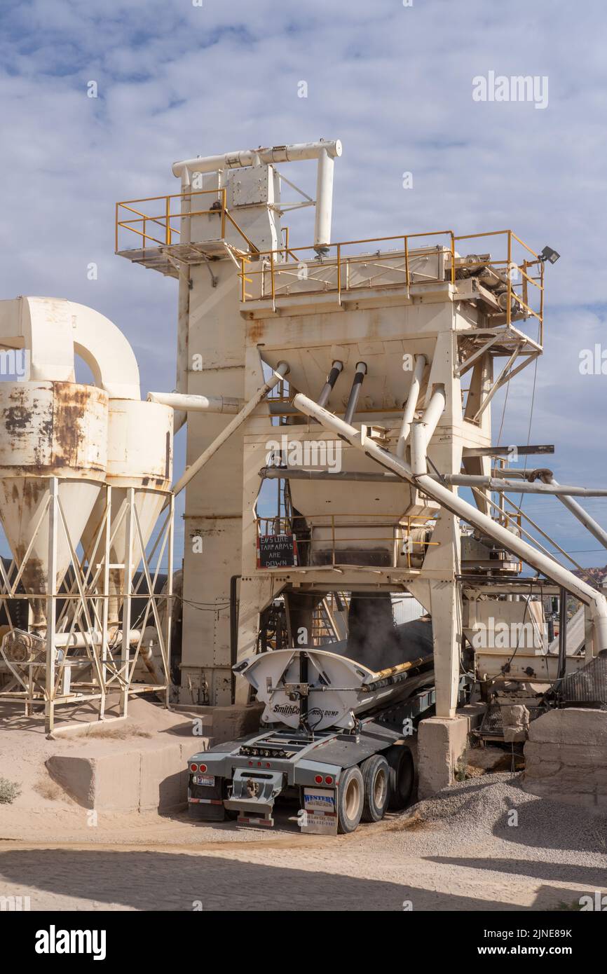 A semi truck gets a load of asphalt from the mixer unit of an asphalt ...