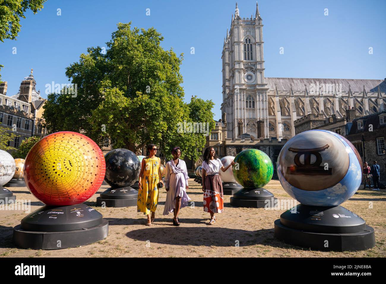 (left to right) Selina Jones, Exhibition Artistic Director Lady Ashley Shaw Scott Adjaye and exhibition founder Michelle Gayle views globe sculptures from 'The World Reimagined', at Dean's Yard at Westminster Abbey, London, ahead of the launch of a new public art trail. The World Reimagined is launching the UK's largest public art trail across seven cities, including London, during which more than 100 artists will unveil globe sculptures reflecting upon colonial histories and the impact of the slave trade on our histories. Picture date: Thursday August 11, 2022. Stock Photo