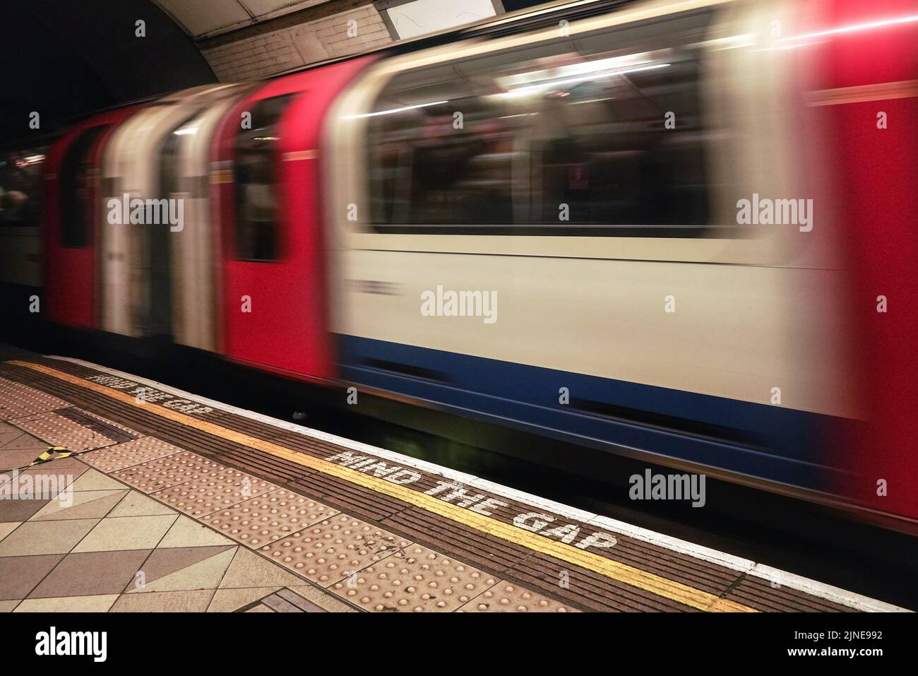 London, United Kingdom - February 01, 2019: MIND THE GAP text on floor of London underground station, blurred train arriving behind white line Stock Photo