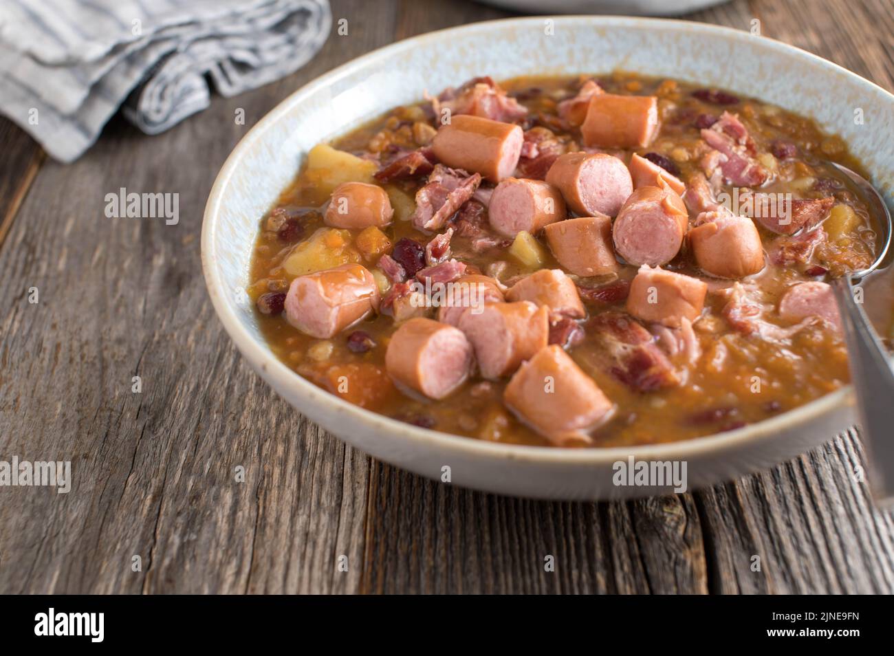Savory meat stew with smoked pork, vienna sausage, potatoes and vegetables Stock Photo