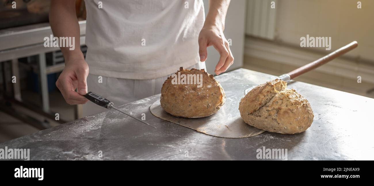 The baker is a man in the process of baking bread. Production of bakery ...