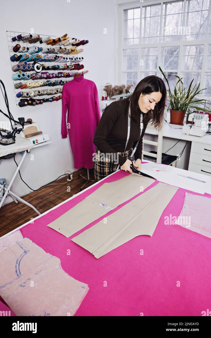 Seamstress working with sewing pattern on table in tailor shop Stock