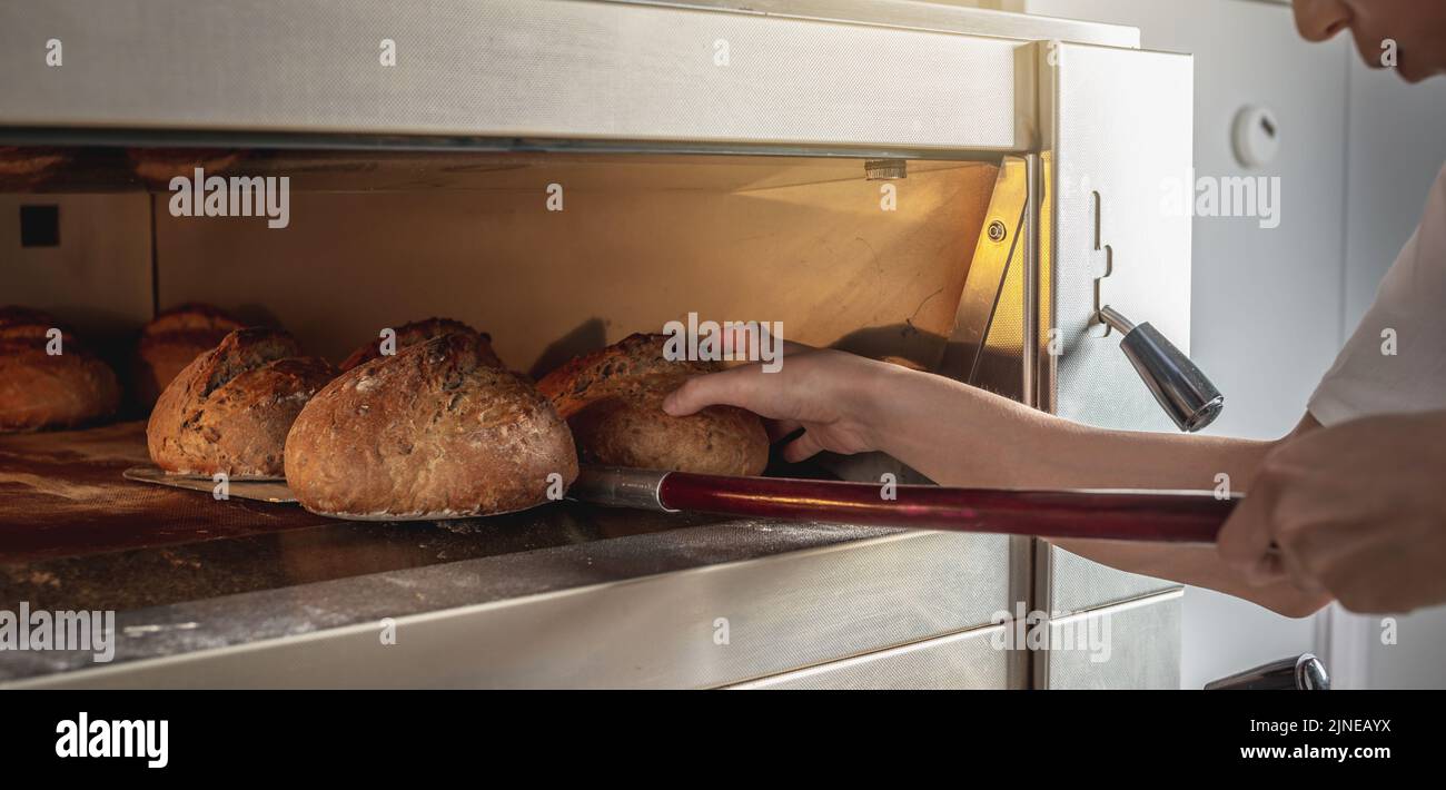 The baker is a man in the process of baking bread. Production of bakery ...