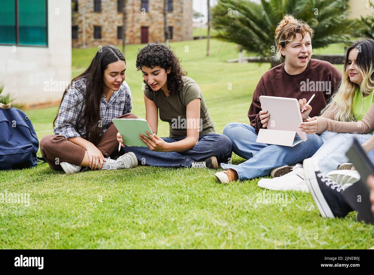 Young friends studying together outdoor sitting in university campus park - Focus on left girls faces Stock Photo