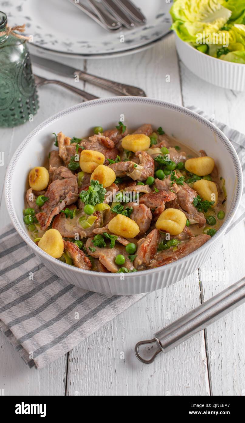 Pork fillet with cream sauce, green peas and potato gnocchi Stock Photo