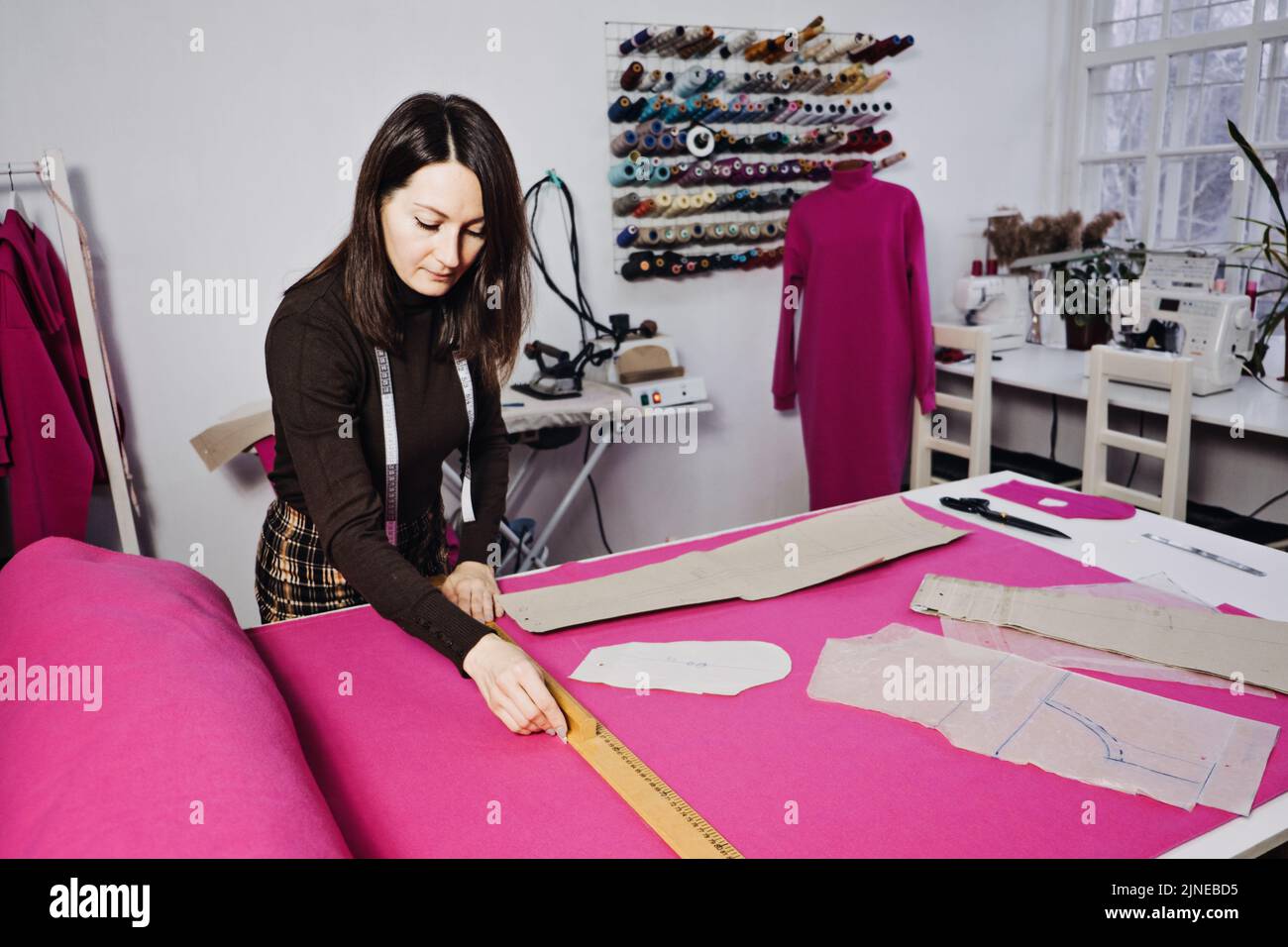 Seamstress working with sewing pattern on table in tailor shop Stock Photo