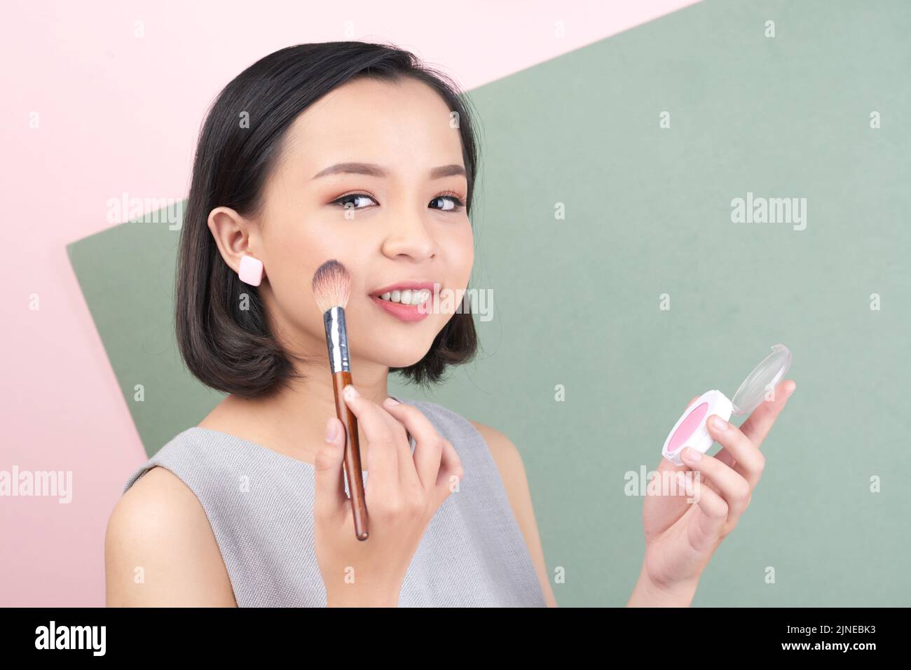 Attractive Vietnamese young woman applying light pink blush Stock Photo