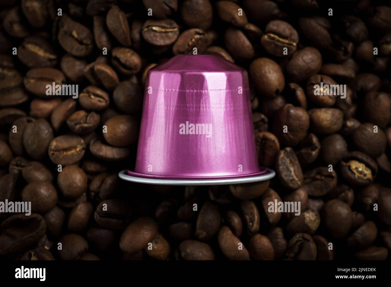 A purple coffee capsule for a machine placed on the coffee beans Stock