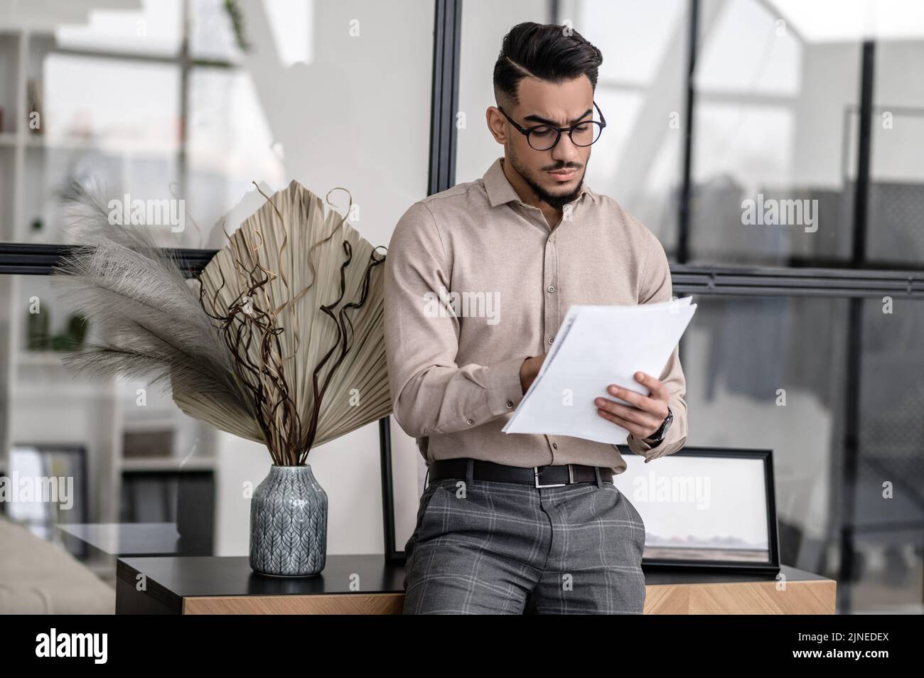 Man attentively looking at papers standing at home Stock Photo