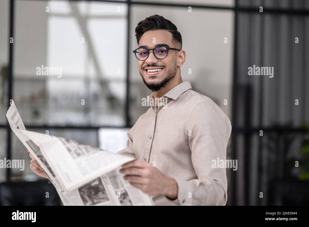 Happy man with newspaper looking at camera Stock Photo
