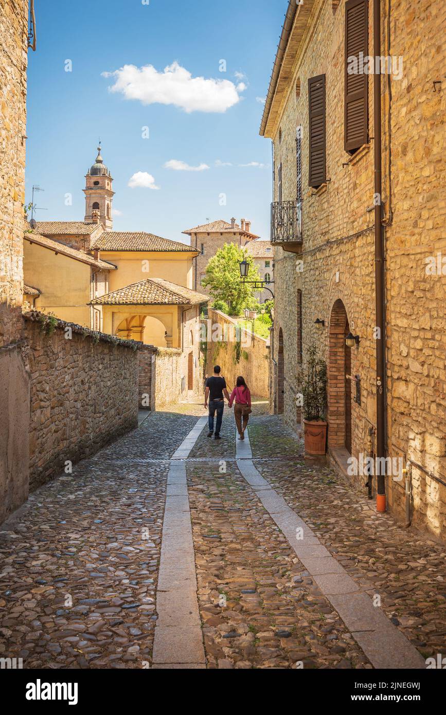 Couple walking a small alley in Castell'Arquato in a sunny day, Piacenza, Italy Stock Photo
