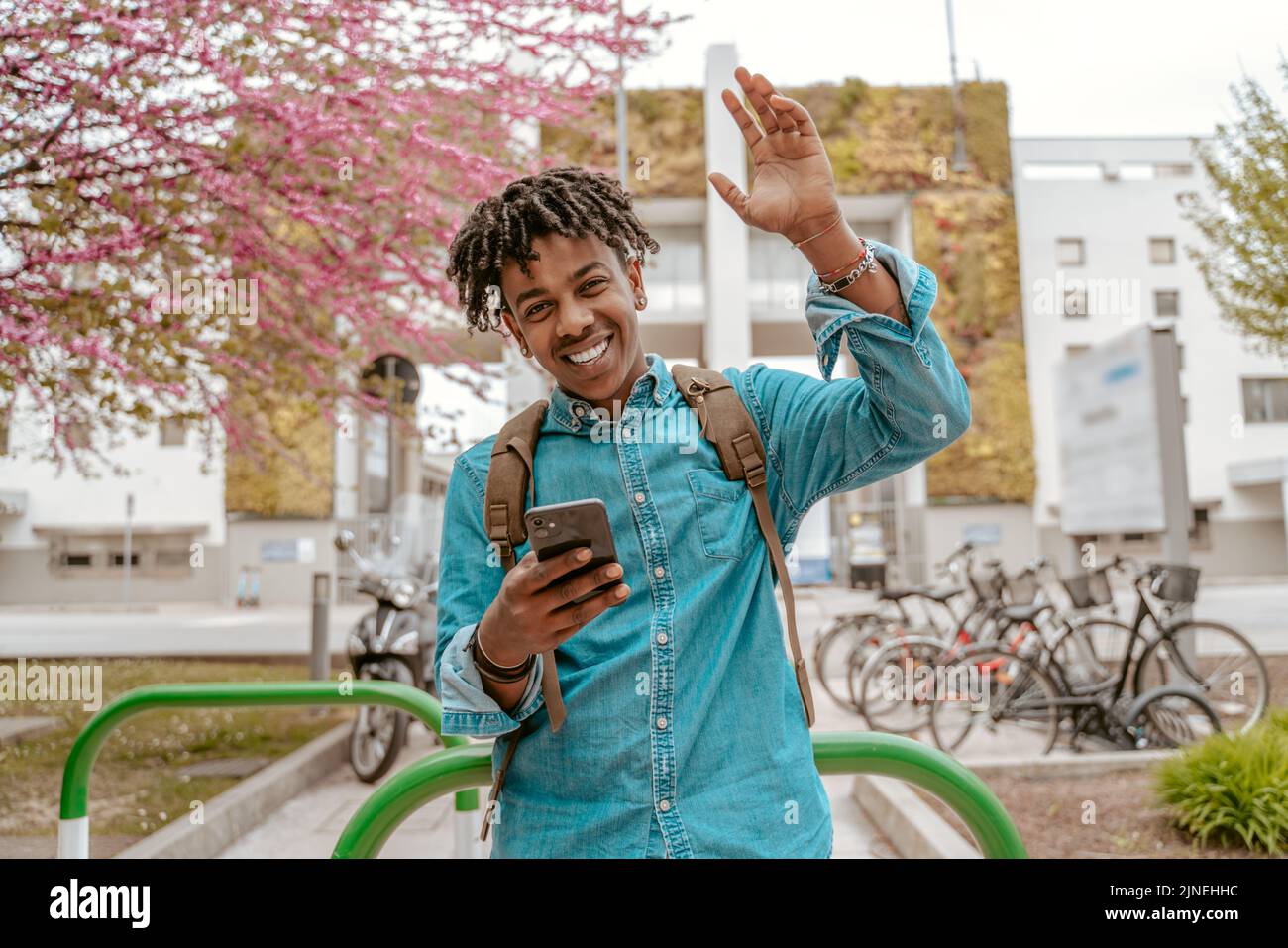 Guy smiling at camera raising hand in greeting Stock Photo