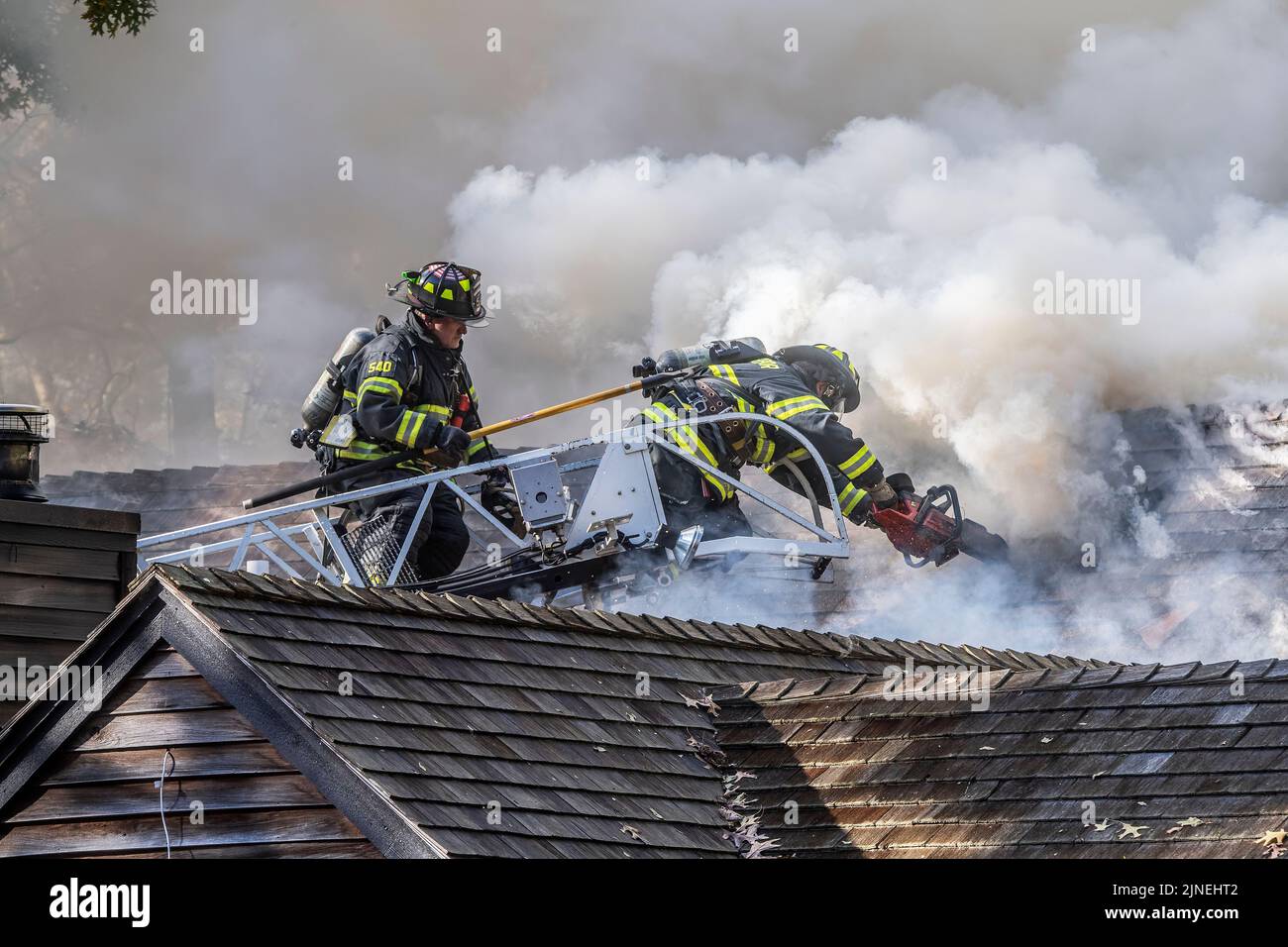 Two Sag Harbor firefighters operating off of an aerial ladder use a