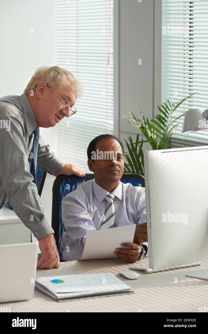 Cheerful multiethnic business colleagues reading information on computer screen Stock Photo