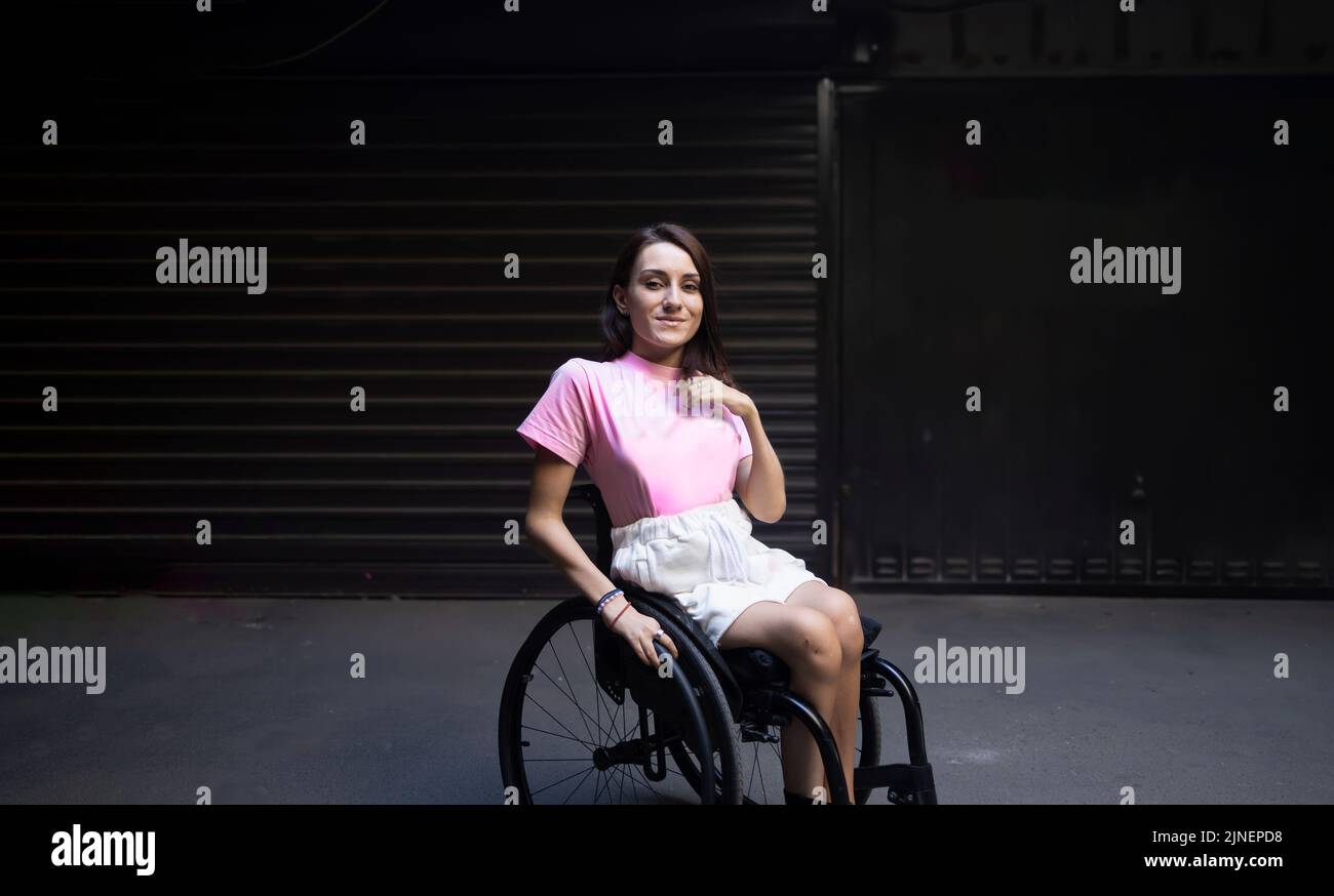 Young strong pretty adult woman smiling in a wheelchair Stock Photo