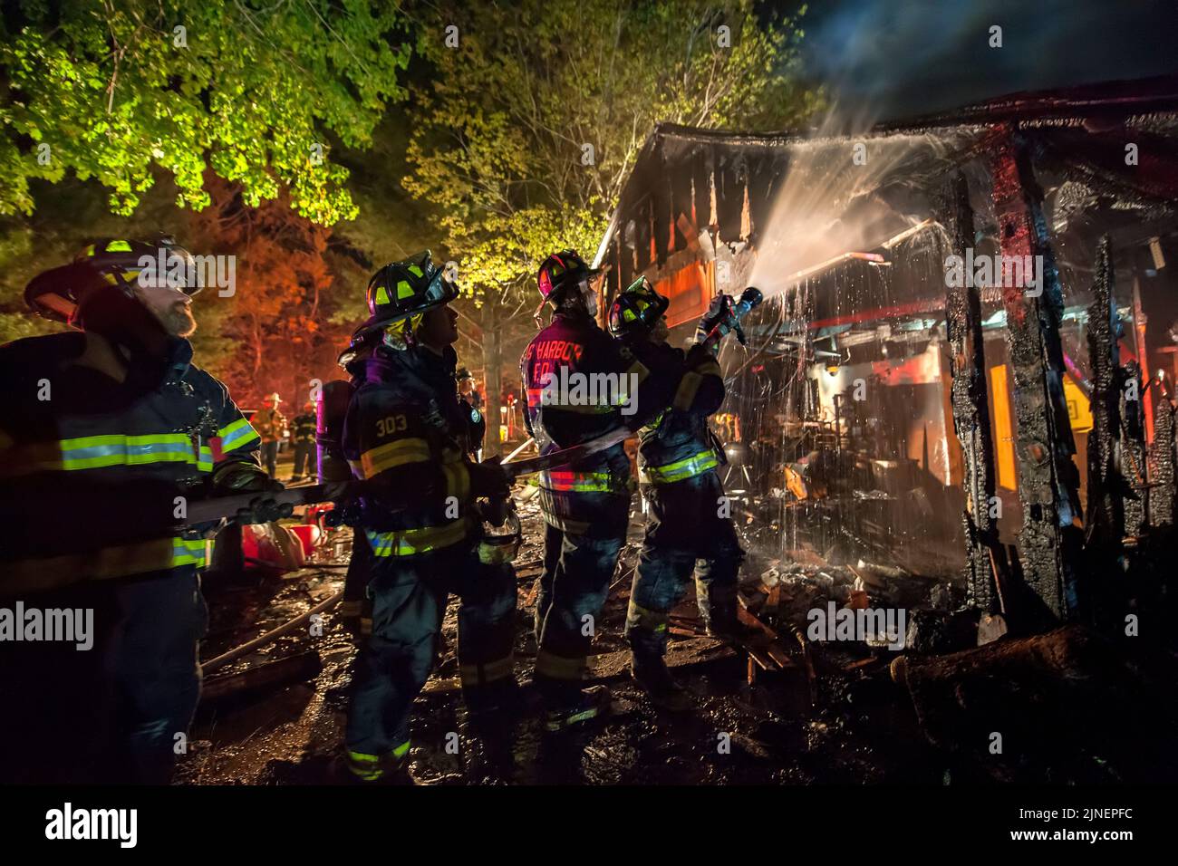 A team of firefighters trains their hose stream on hot spots inside the garage as at 10:16 p.m. on Wednesday, May 18th, 2016 the Sag Harbor Fire Depar Stock Photo