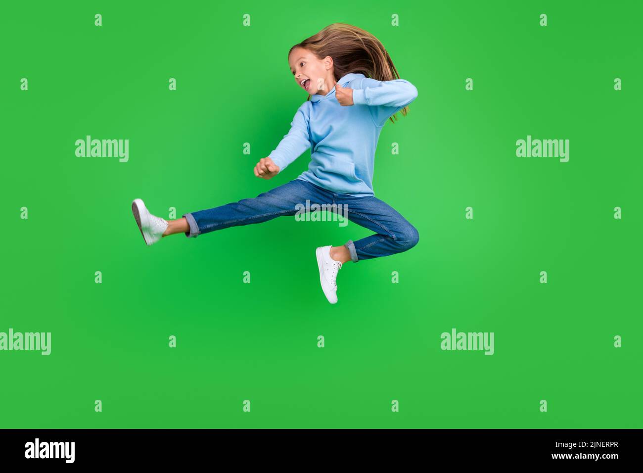 Full body photo of energetic small girl jump practicing martial arts fan dressed trendy blue sportswear isolated on green color background Stock Photo