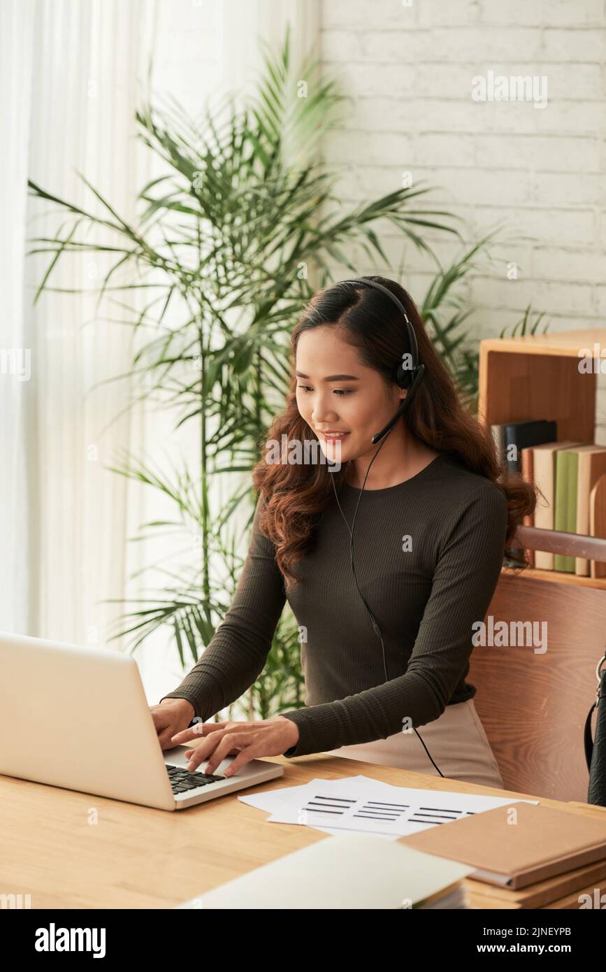 Cheerful pretty business lady in headset working on computer Stock ...