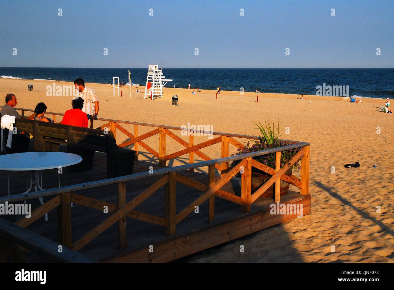 Friends gather on a deck over looking Main Beach in East Hamptons, one of the top beaches in The Hamptons, towards the end of a summer vacation day Stock Photo