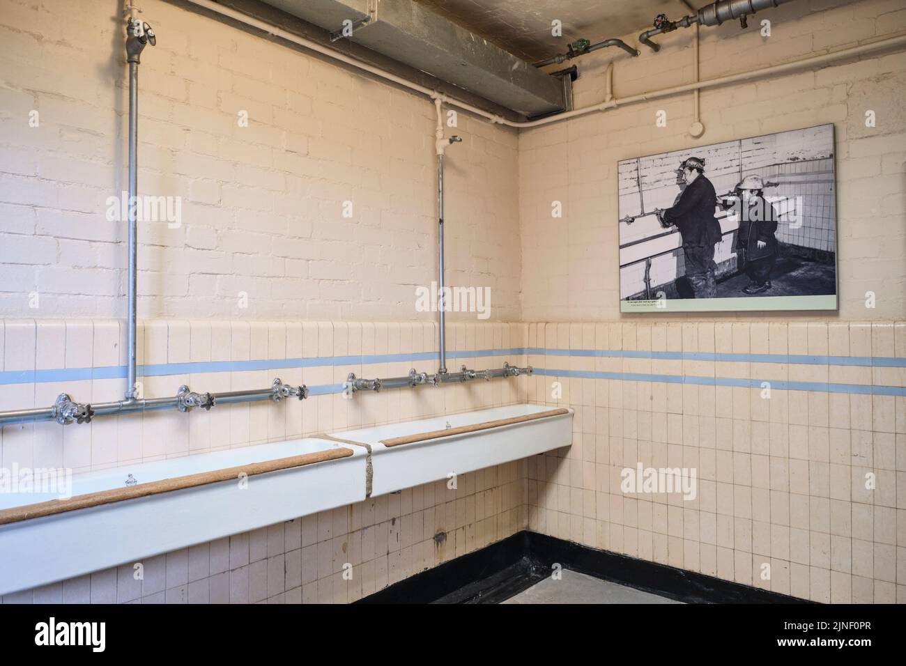 Big, communal, trough tiled sinks, for miners to use for washing hands, arms before entering the locker, changing area. At the Big Pit National Coal M Stock Photo