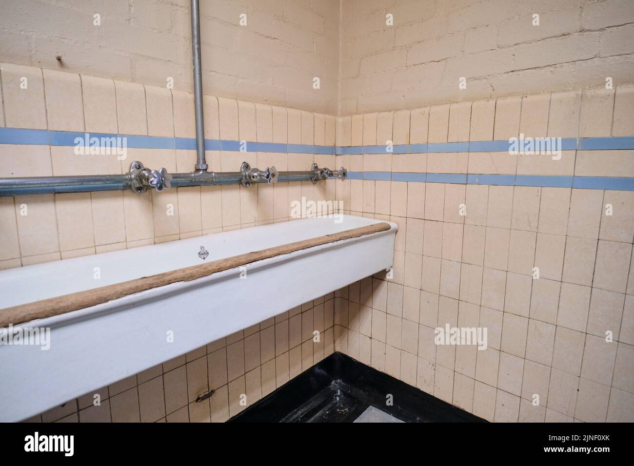 Big, communal, trough tiled sinks, for miners to use for washing hands, arms before entering the locker, changing area. At the Big Pit National Coal M Stock Photo