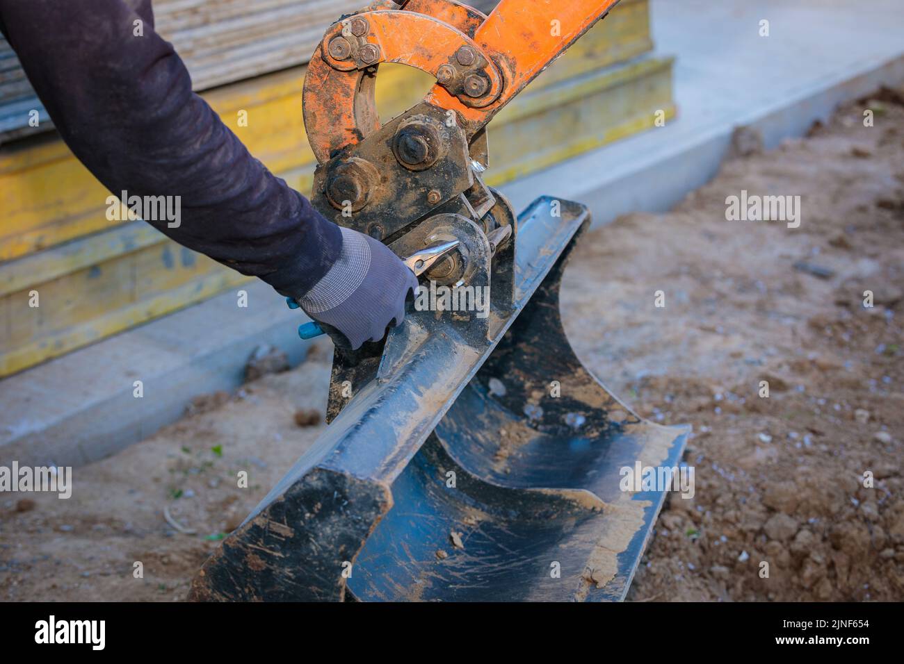Tractor Rear Bucket Moving A man repairs a tractor bucket, changes the mounting sleeve. Replacing ...