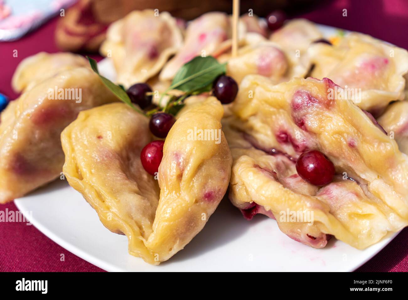 Ukrainian varenyky with cherries in a white plate of white tablecloth. Hard light. Selective focus. Close-up Stock Photo